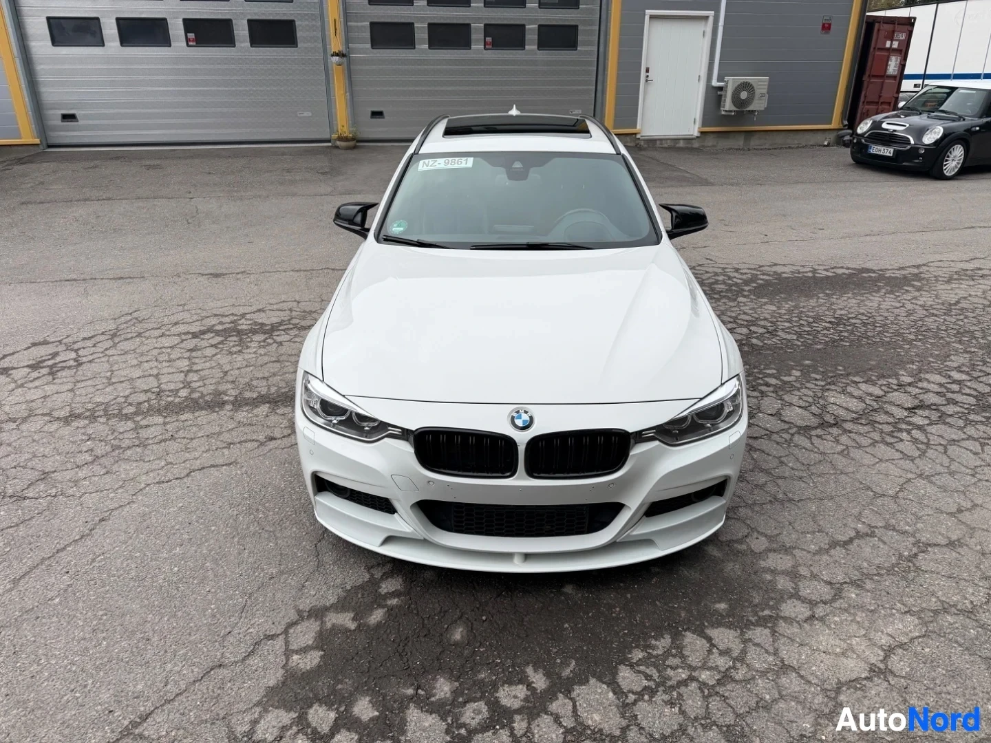 Valkoinen BMW farmari suoraan edestä kuvattu, musta säleikkö, parkkipaikalla