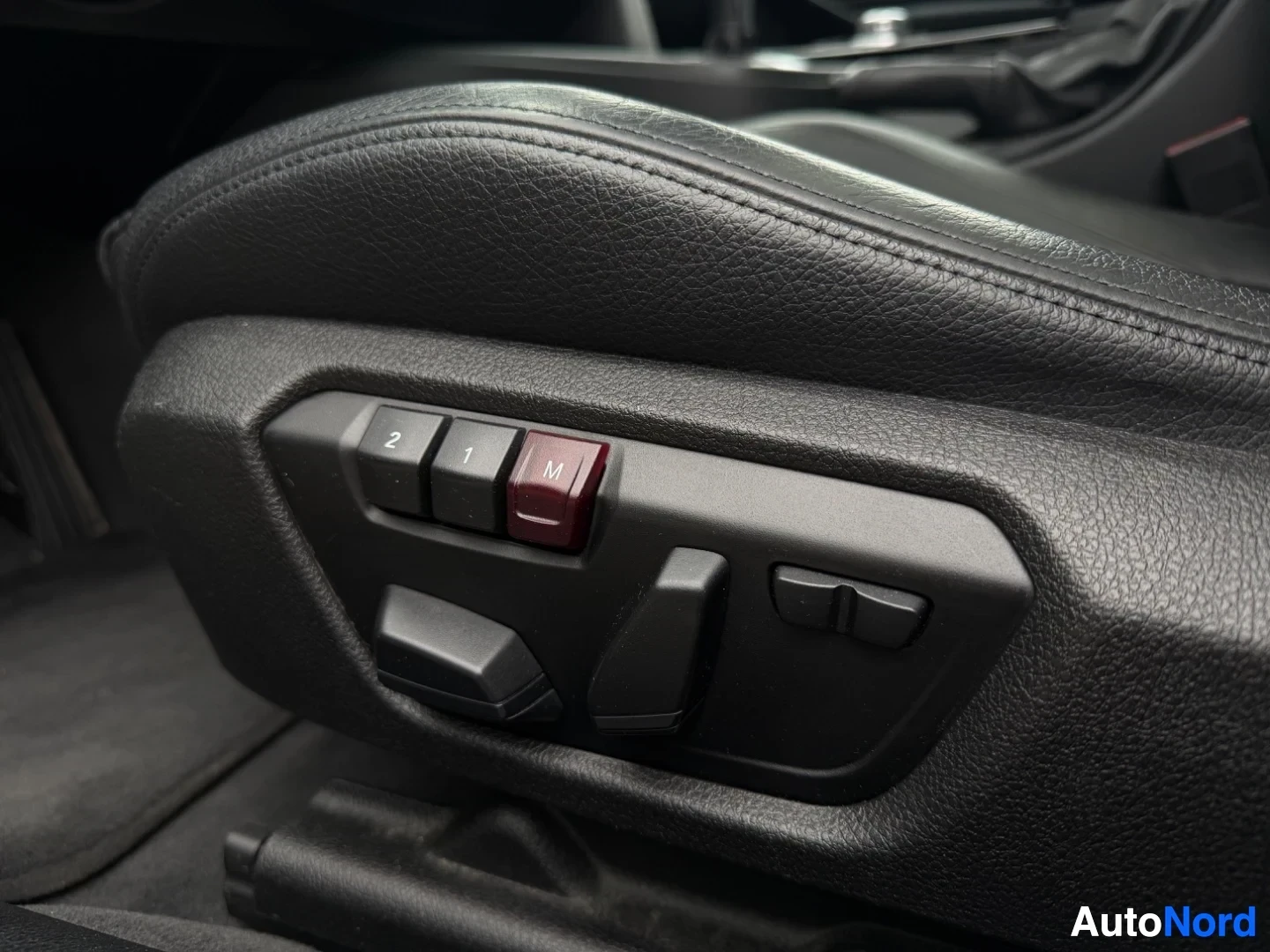 Black leather seat with electric adjustment controls and M button.
