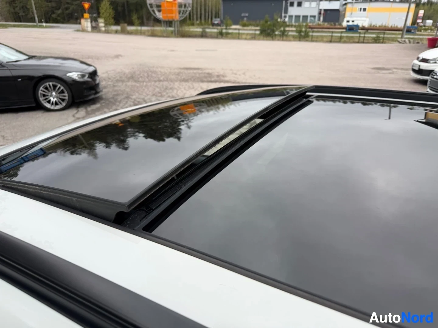 Panoramic sunroof with black frame on white car roof.