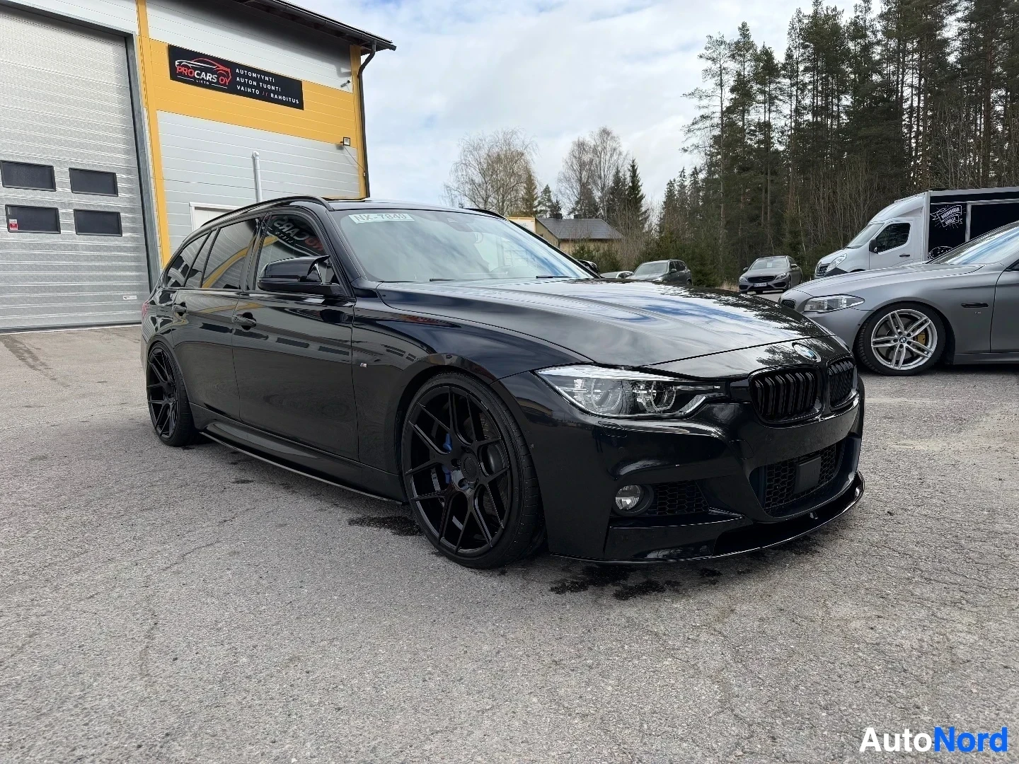 Musta farmari näkyy vasemmalta edestä autoliikkeen pihalla
