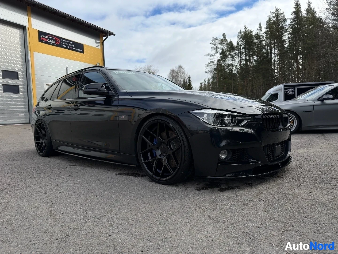 Musta BMW farmari kuvattu edestä vasemmalta puolelta parkkipaikalla