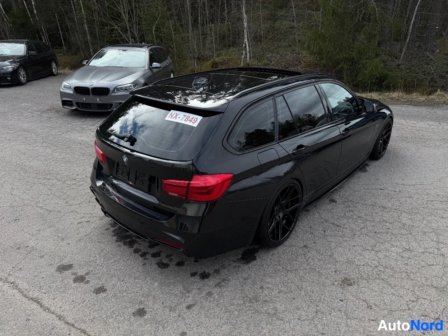 Musta BMW farmari näkyy takavasemmalta, rekisterikilvellä näkyvissä.