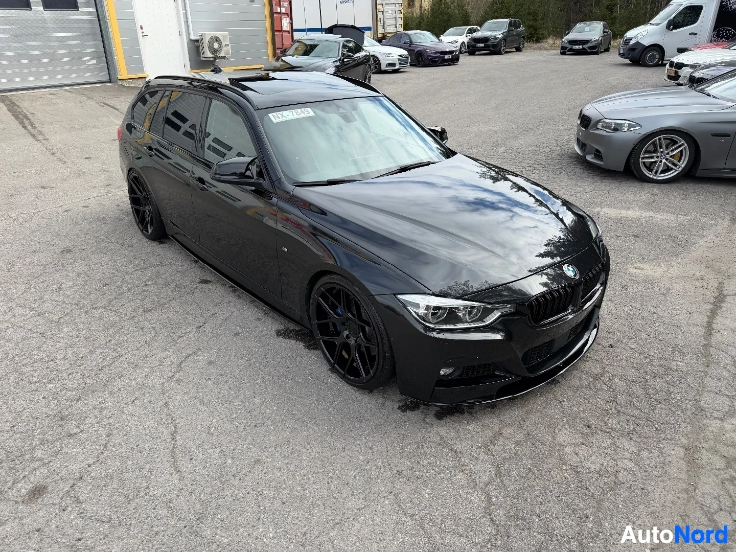 Etuviisto, nokka oikealle: Musta BMW 3-sarjan farmari kolmesta neljäsosan etukulmasta, mustat vanteet, AutoNord-pihalla.