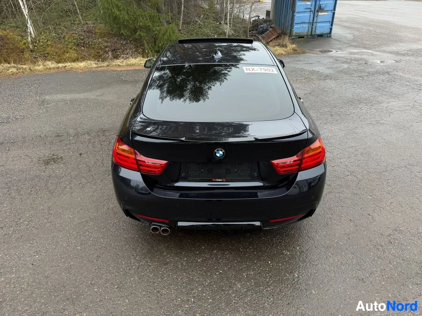 Musta BMW coupe suoraan takaa, punaiset takavalot ja kaksoisputkipäästö