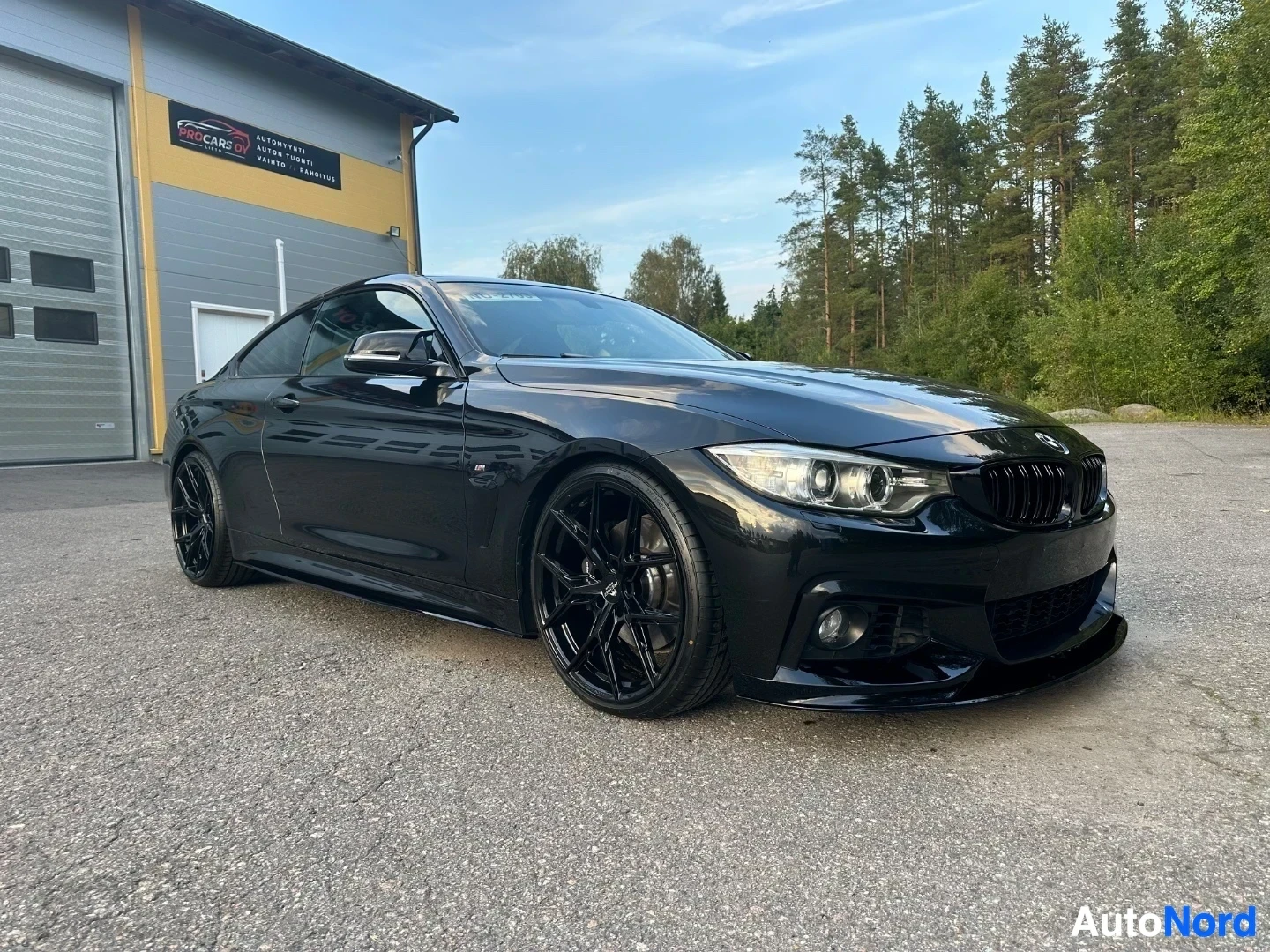 Black BMW coupe photographed from front-left angle in daylight