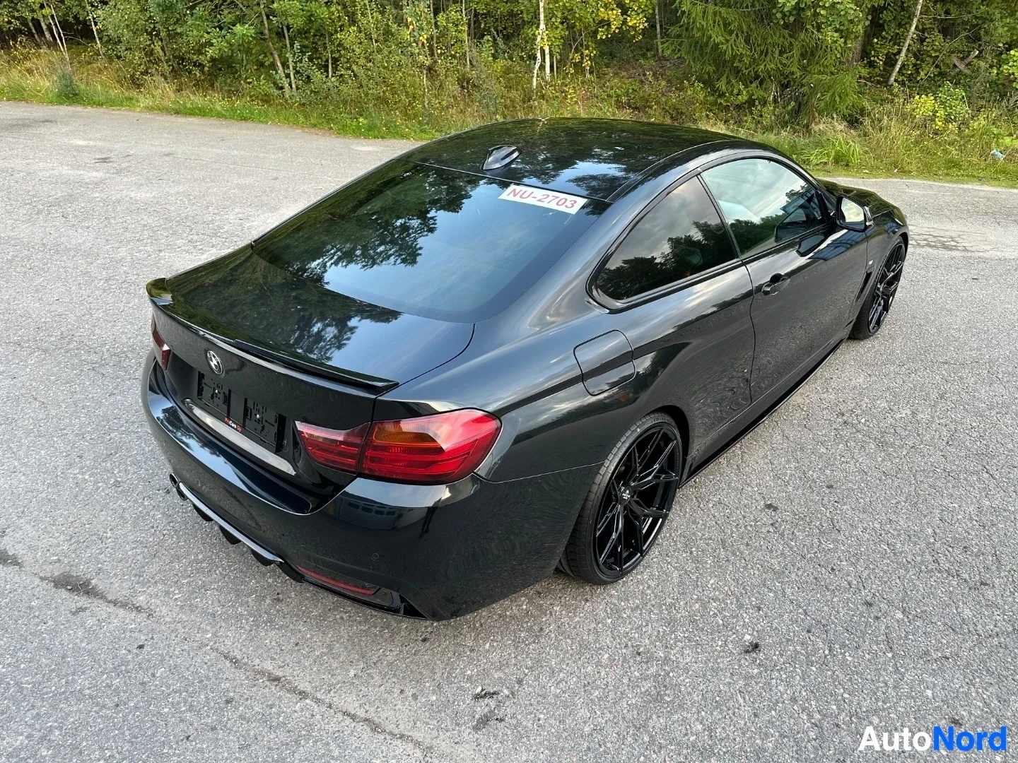 Black BMW coupe rear three-quarter view on asphalt, red taillights visible
