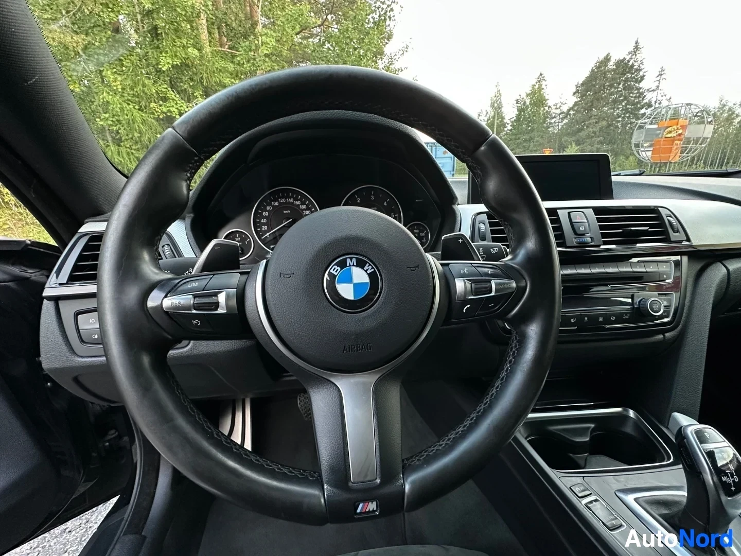 Ohjauspyörä, mittaristopaneeli ja BMW-logolla varustettu sisätilanne