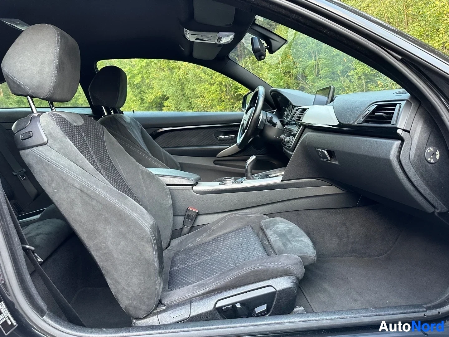 Interior front view showing steering wheel, dashboard, and textured front seats