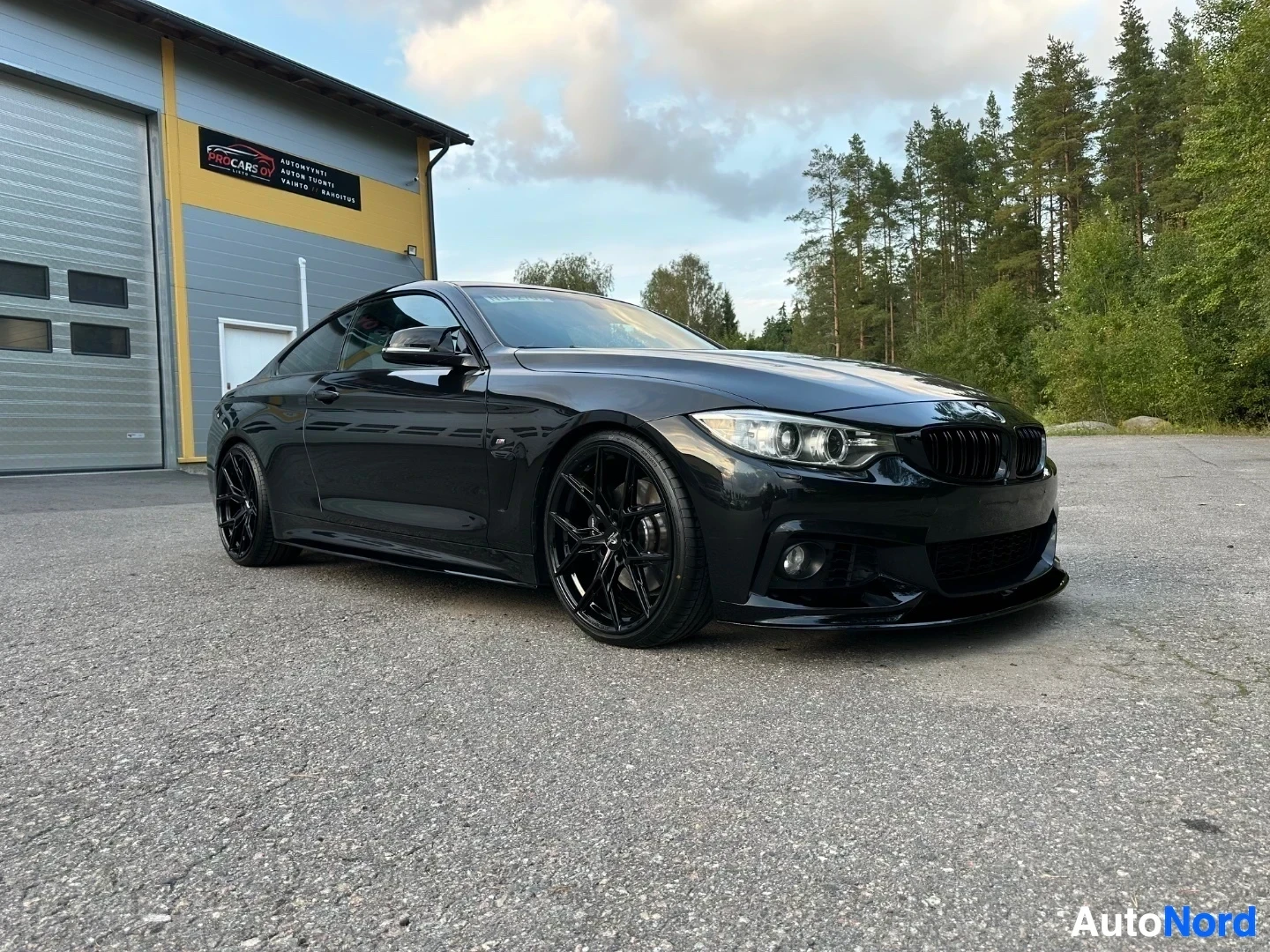 Black BMW coupe front three-quarter view with LED headlights and front splitter
