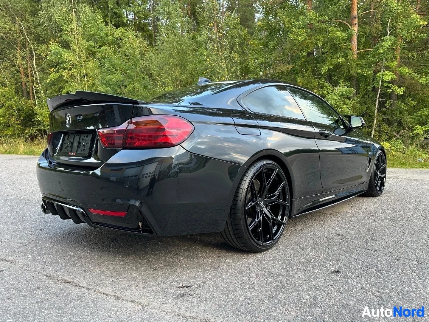 Black coupe rear three-quarter view with open trunk and rear spoiler visible
