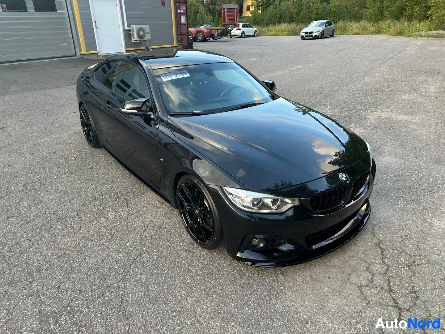Black BMW coupe parked on asphalt, angled three-quarter front view