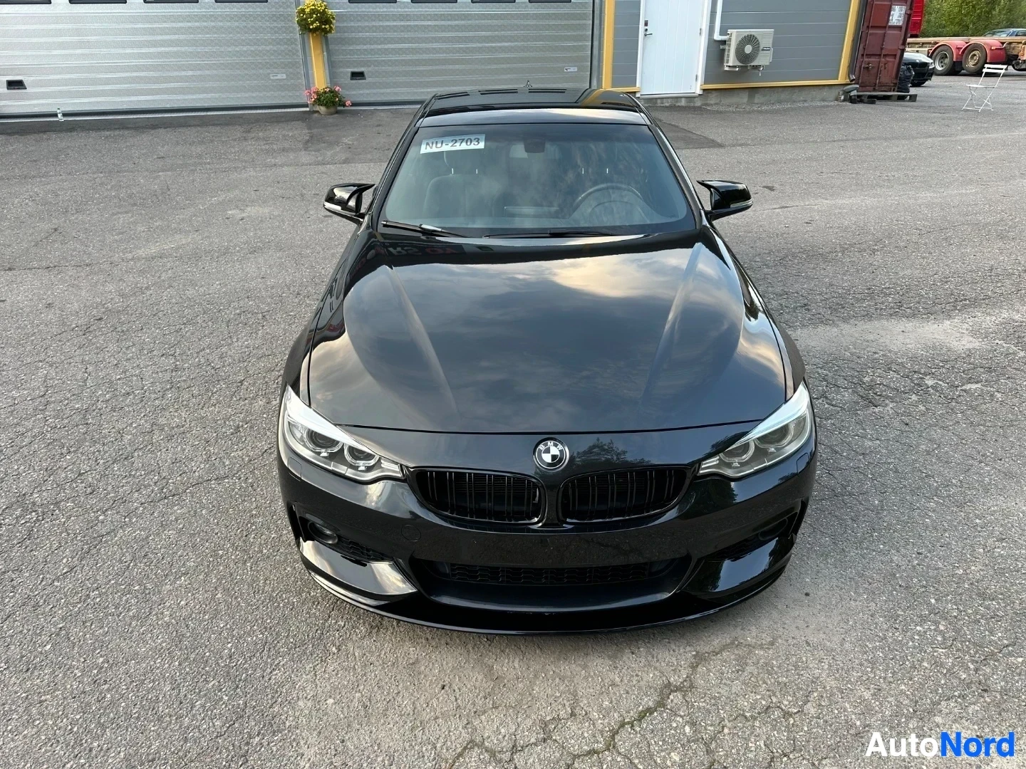 Black BMW coupe photographed from front, straight-on view showing grille and headlights