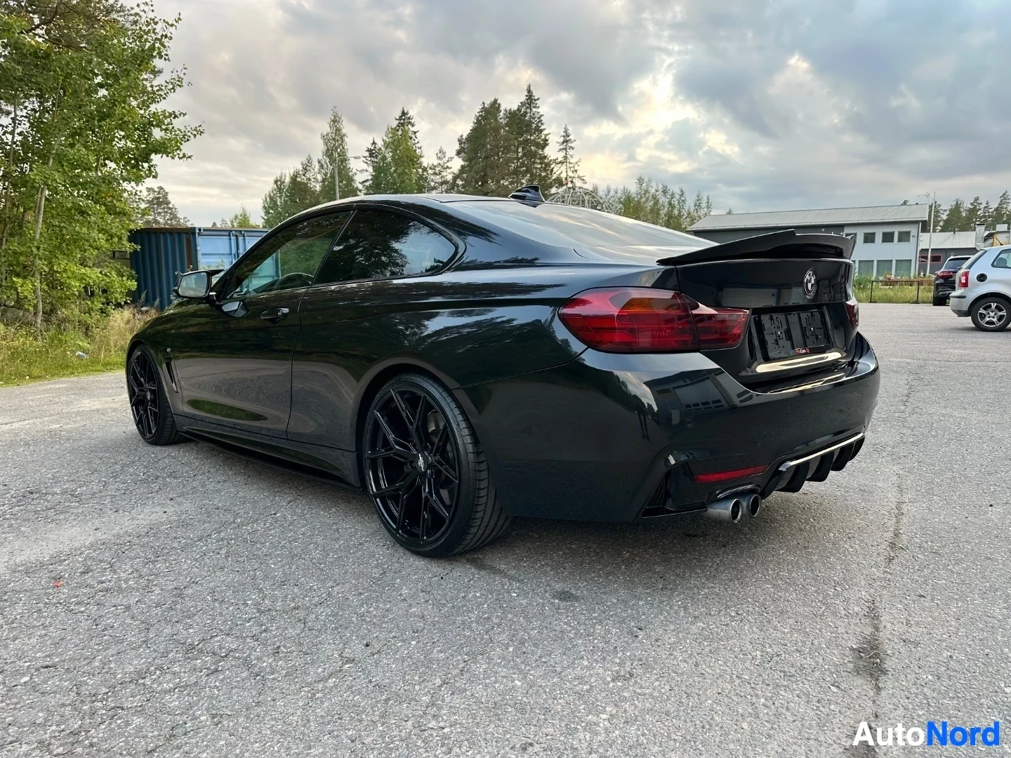 Black coupe rear three-quarter view showing trunk and taillights open