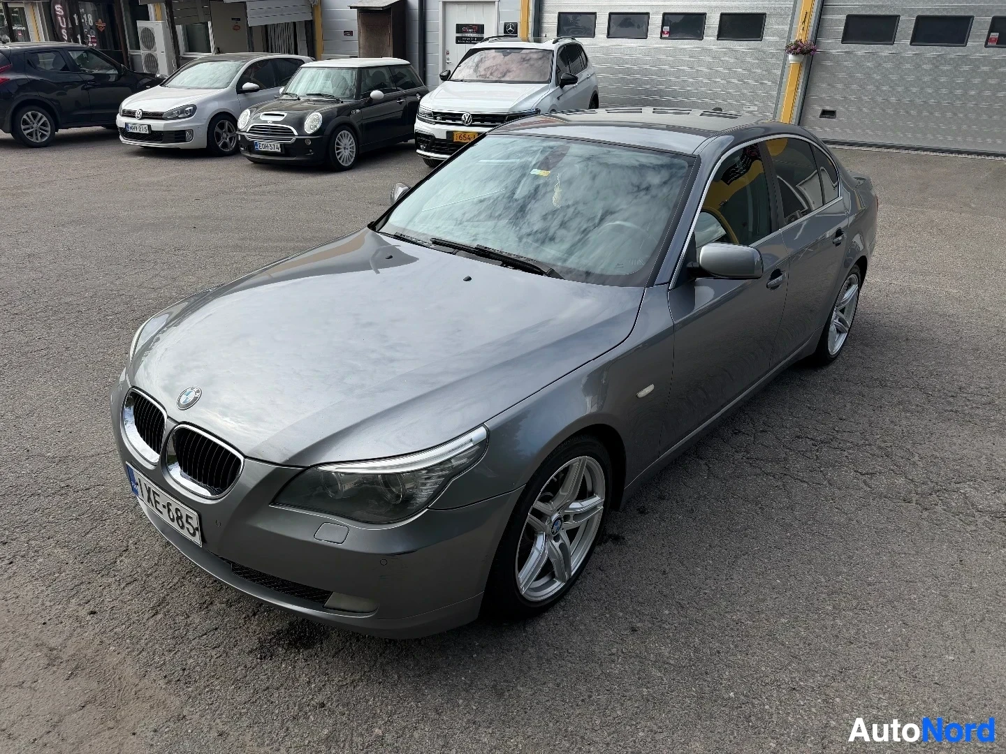 Harmaa BMW sedan näkyy vasemmalta sivusta parkkipaikalla