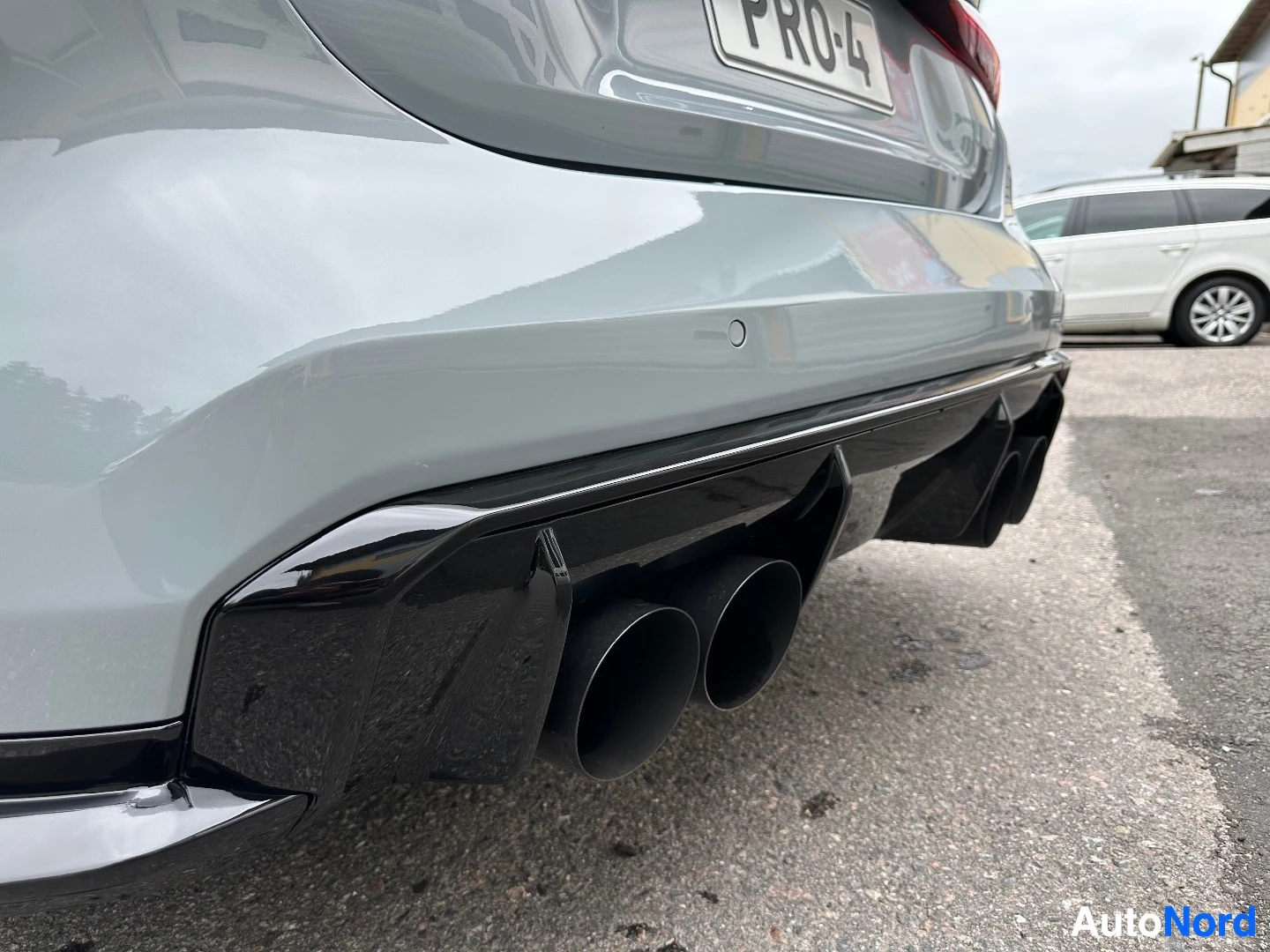Dual exhaust pipes and diffuser on rear bumper of white coupe