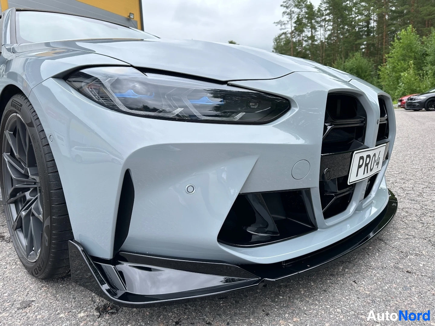 White BMW coupe front left angle showing headlight, grille, and black aerodynamic front splitter