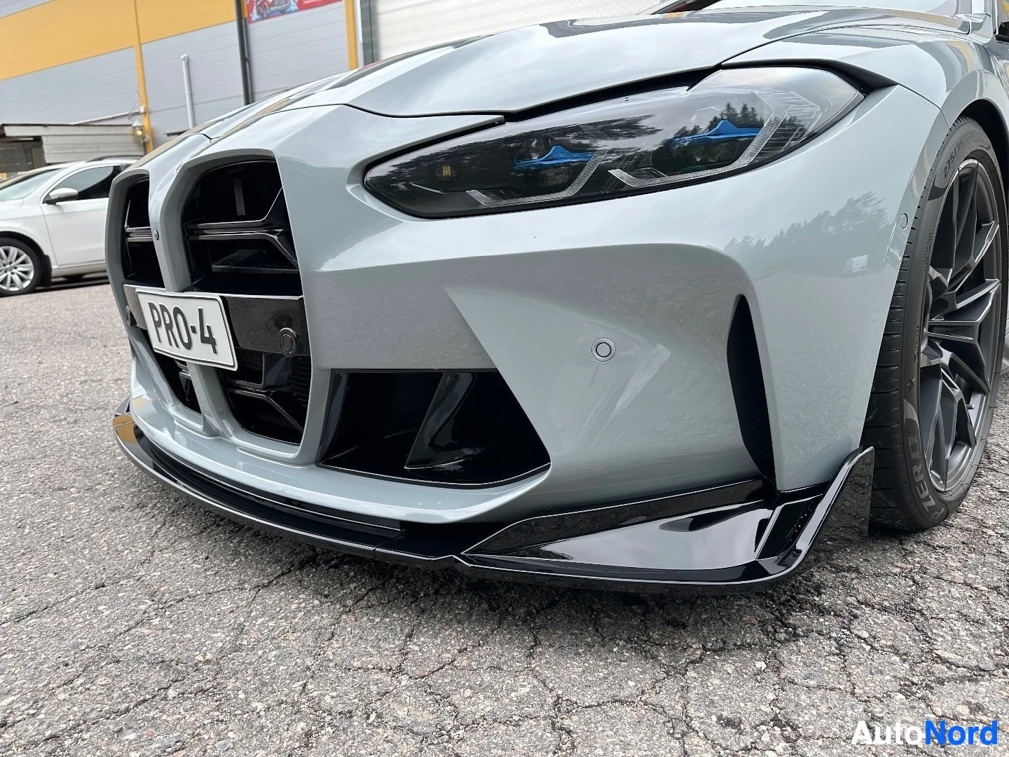 White BMW coupe front left angle with open door, showing black front bumper and aerodynamic elements