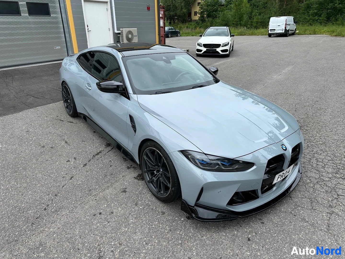 Valkoinen BMW M4 edestä vasemmalle, sinisten LED-ajovalojen näkyvillä