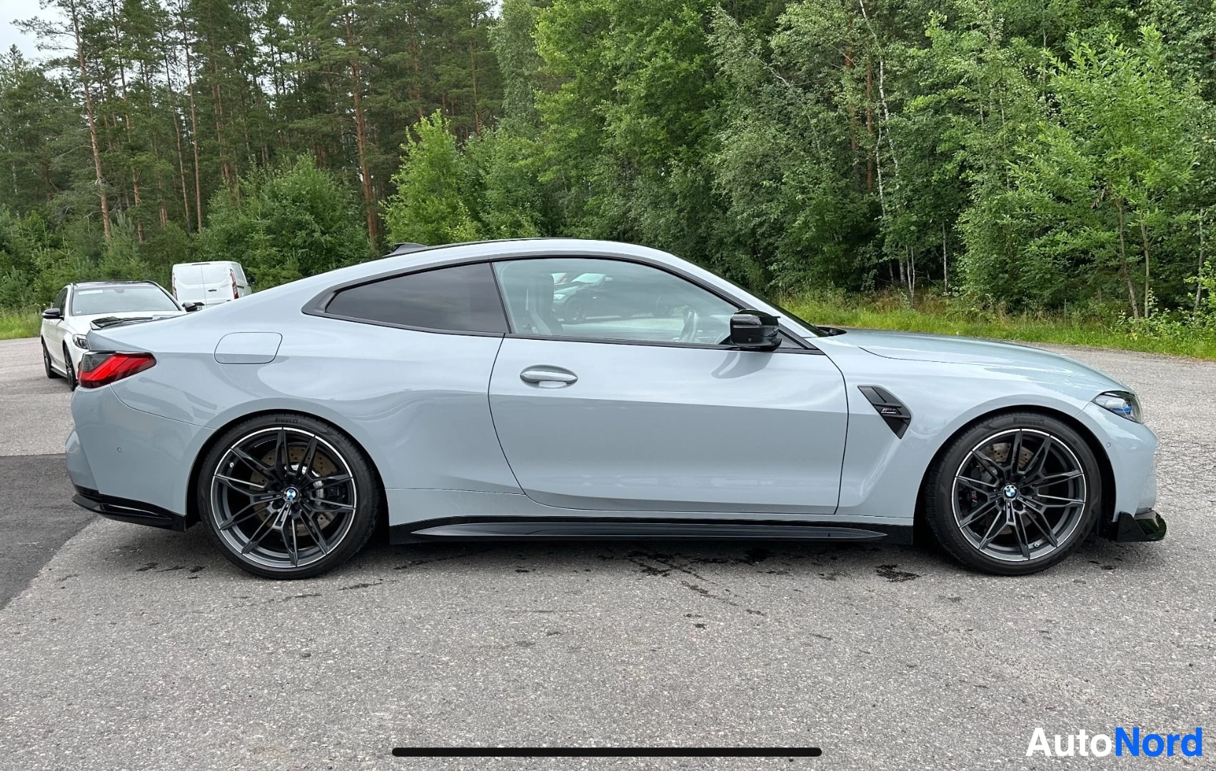 Valkoinen BMW M4 sivusta vasemmalle, tummat vanteet näkyvillä