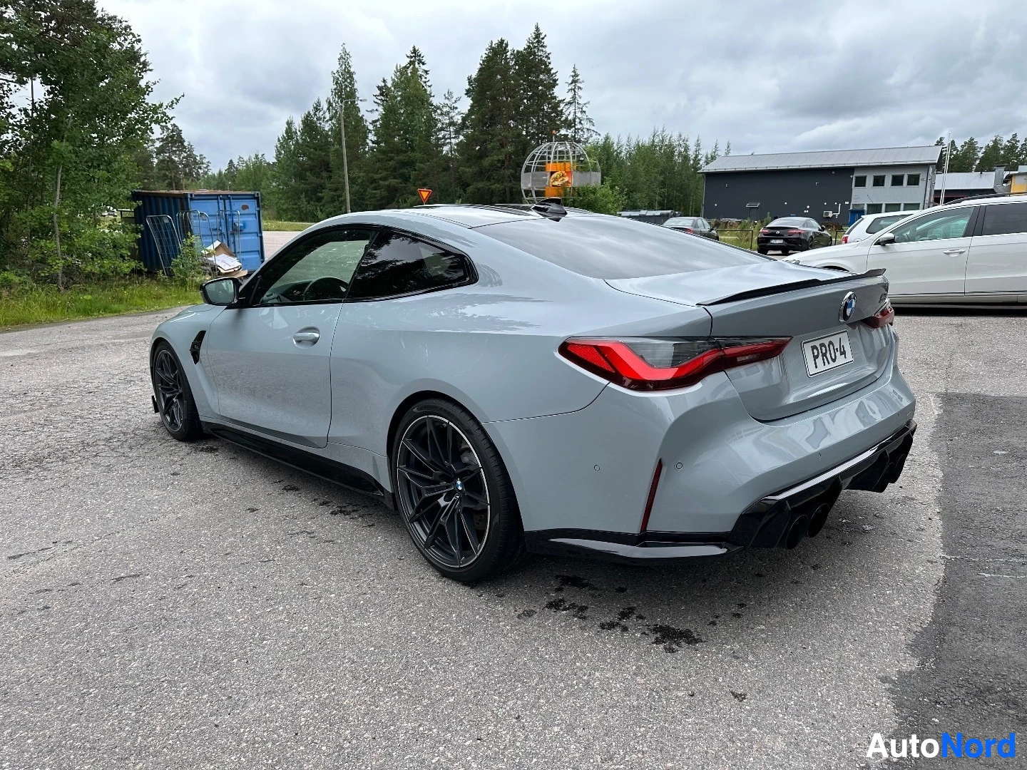 White BMW M4 coupe rear quarter view showing taillights and spoiler, parked outside