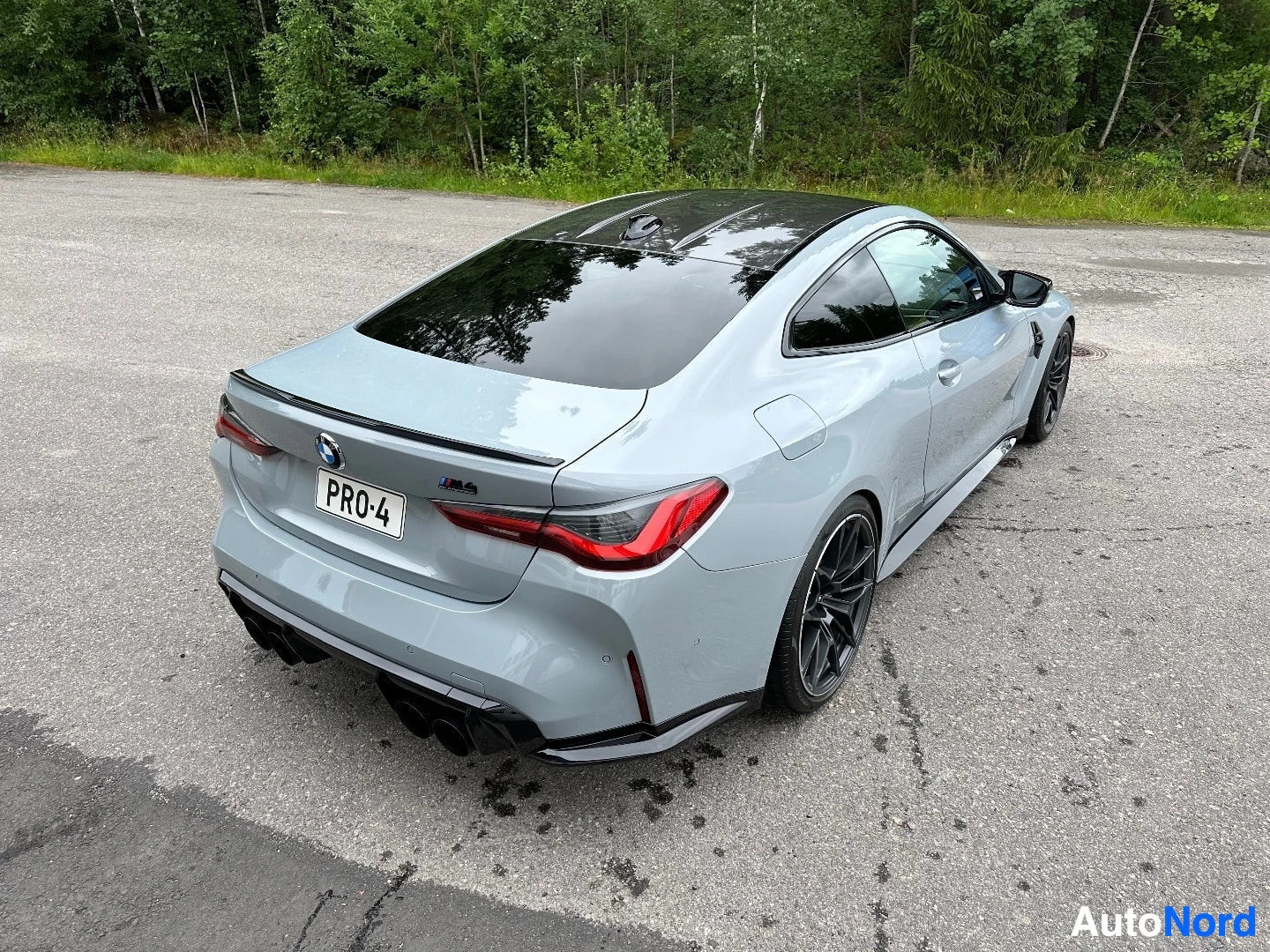 Valkoinen BMW M4 kolmiulotteisesta takaosasta, punaisten takavalojen näkyvillä