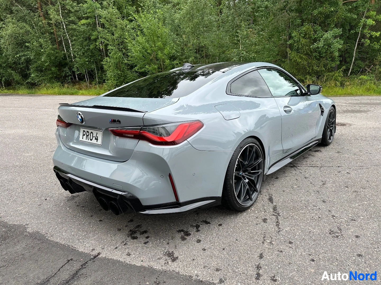 Valkoinen BMW M4 takaosasta vasemmalle, punaisten takavalojen näkyvillä