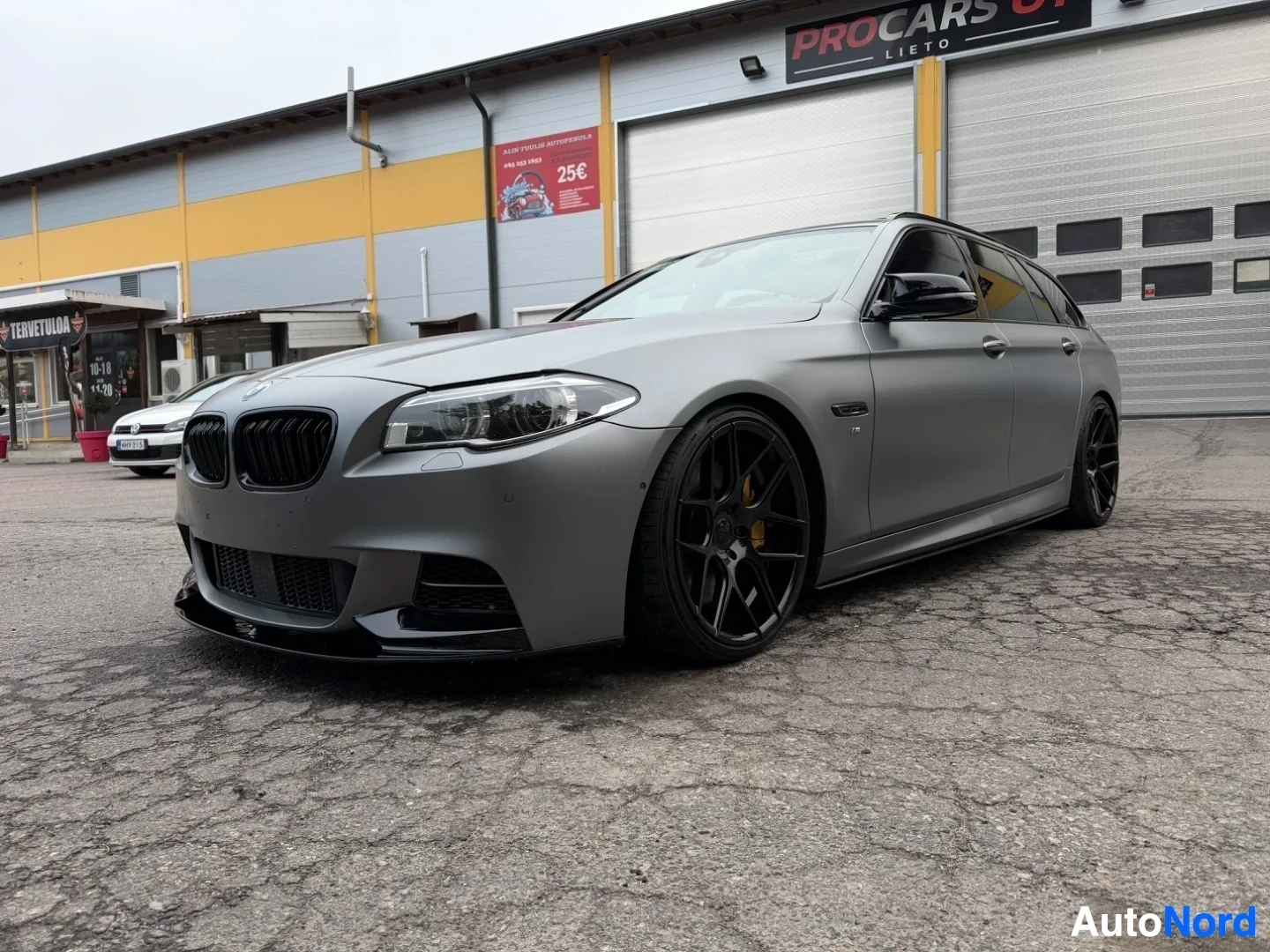 Harmaa BMW farmari näkyy edestä vasemmalta kulmasta varikolla