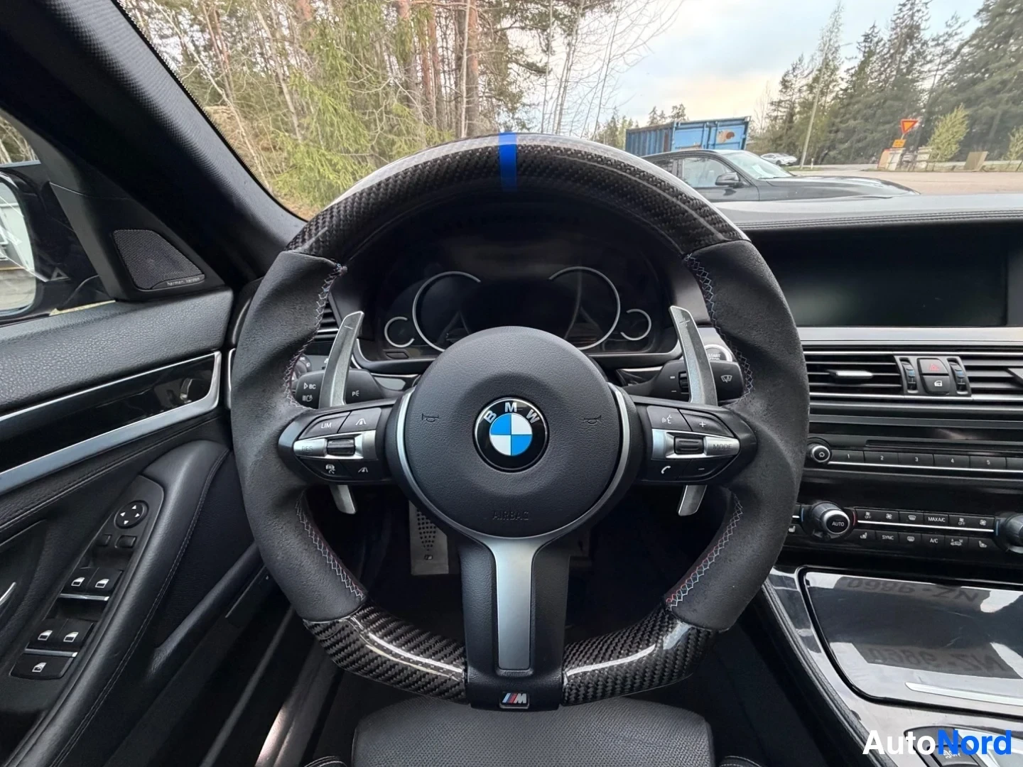 Steering wheel with BMW logo and carbon fiber trim, dark interior
