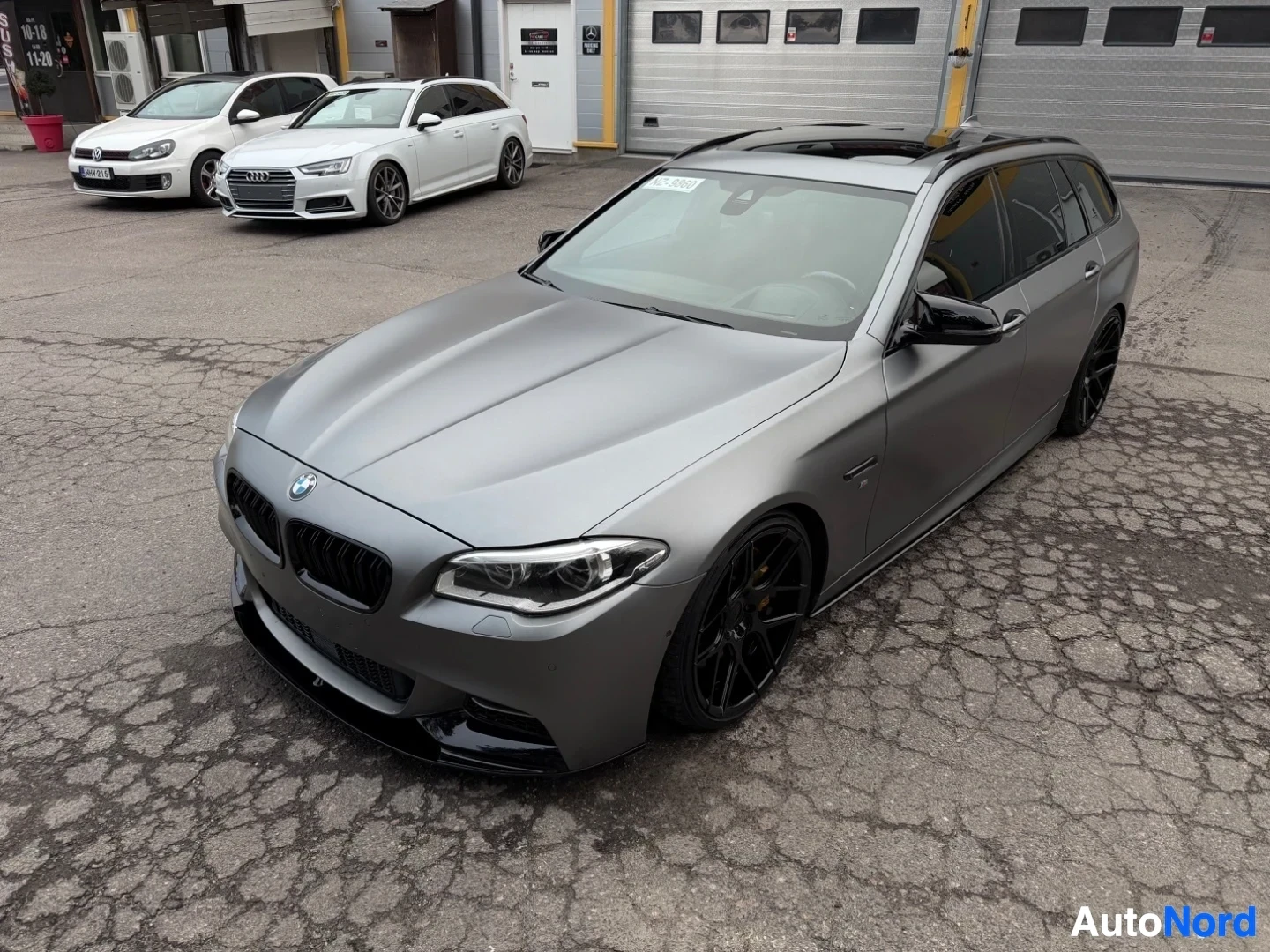Harmaa BMW farmari näkyy ylhäältä edestä varikolla