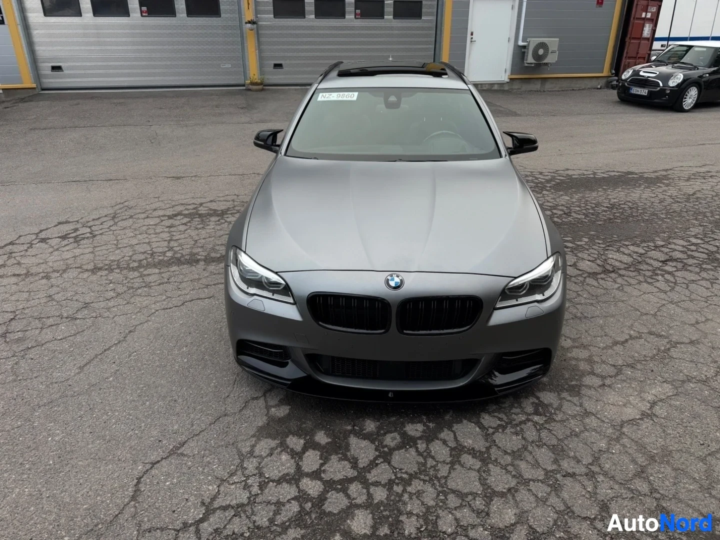 Silver BMW sedan viewed from front, parked in dealer lot