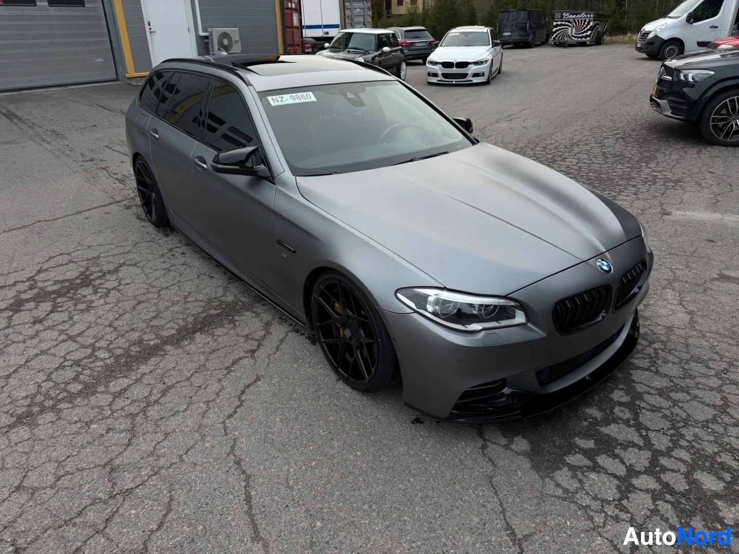 Silver BMW estate wagon viewed from front-left, parked in dealer lot