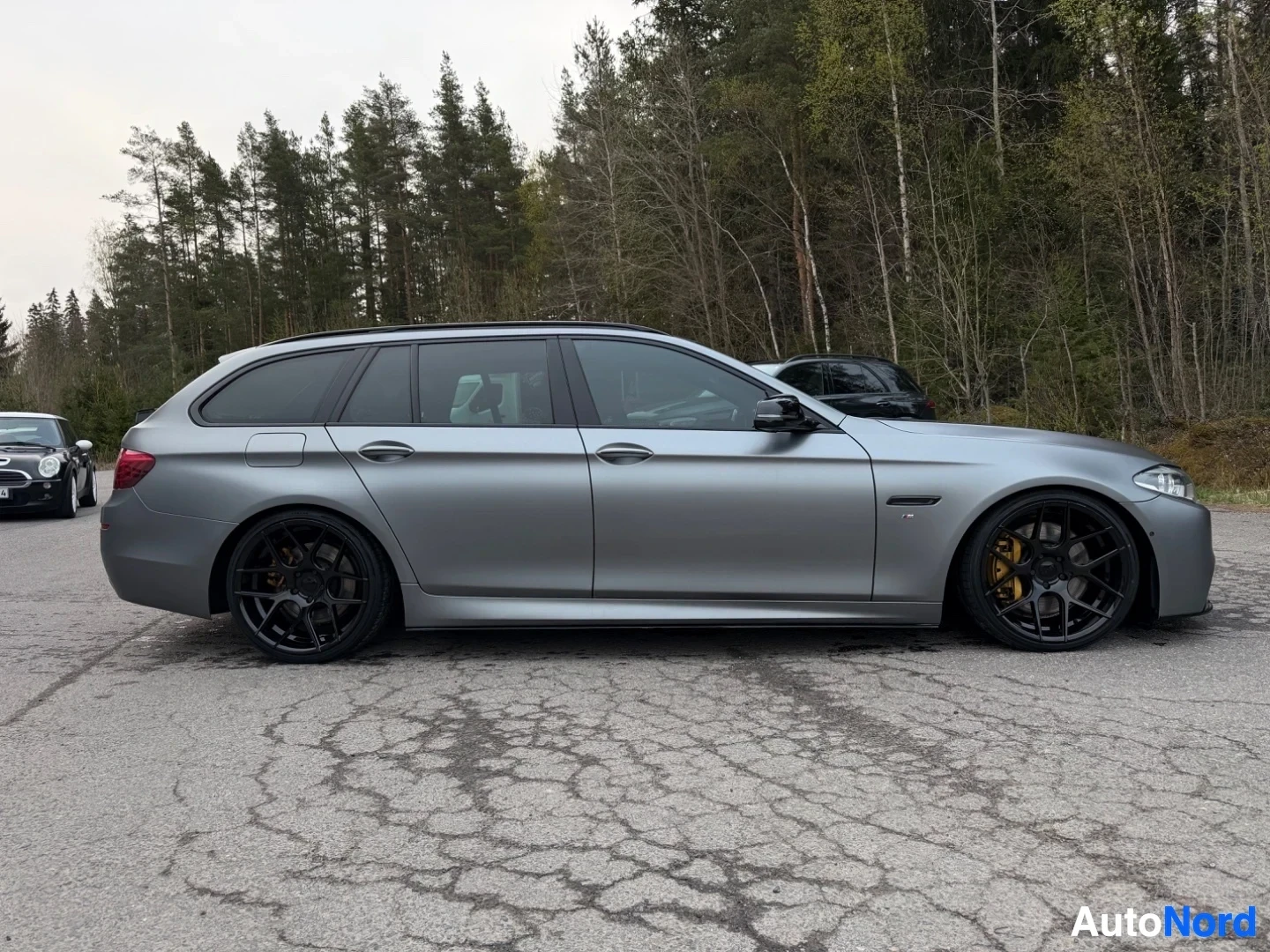 Silver BMW estate wagon profile view, showing full side with black wheels