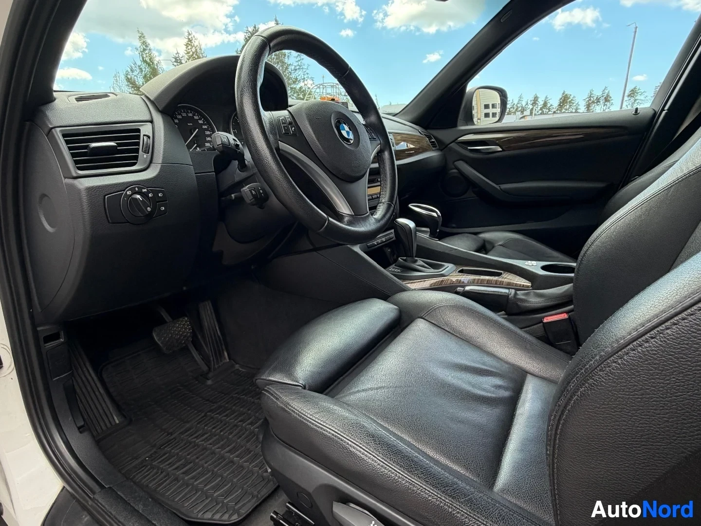 Cockpit view with black leather seats, steering wheel, and dashboard controls.