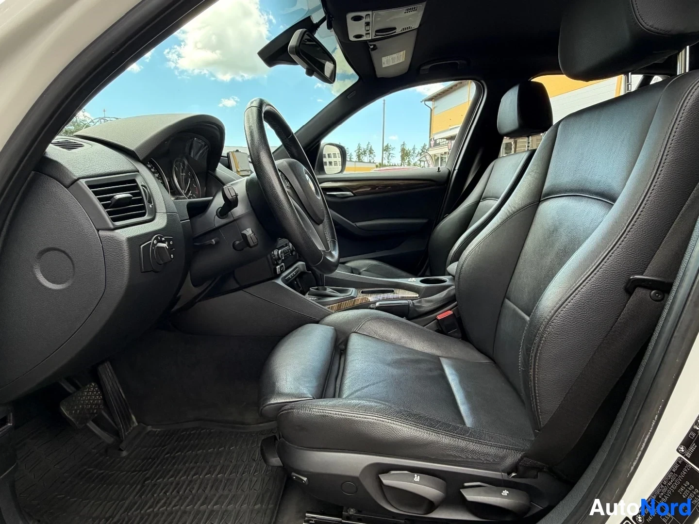 Interior side view showing black leather seating and wood trim dashboard.