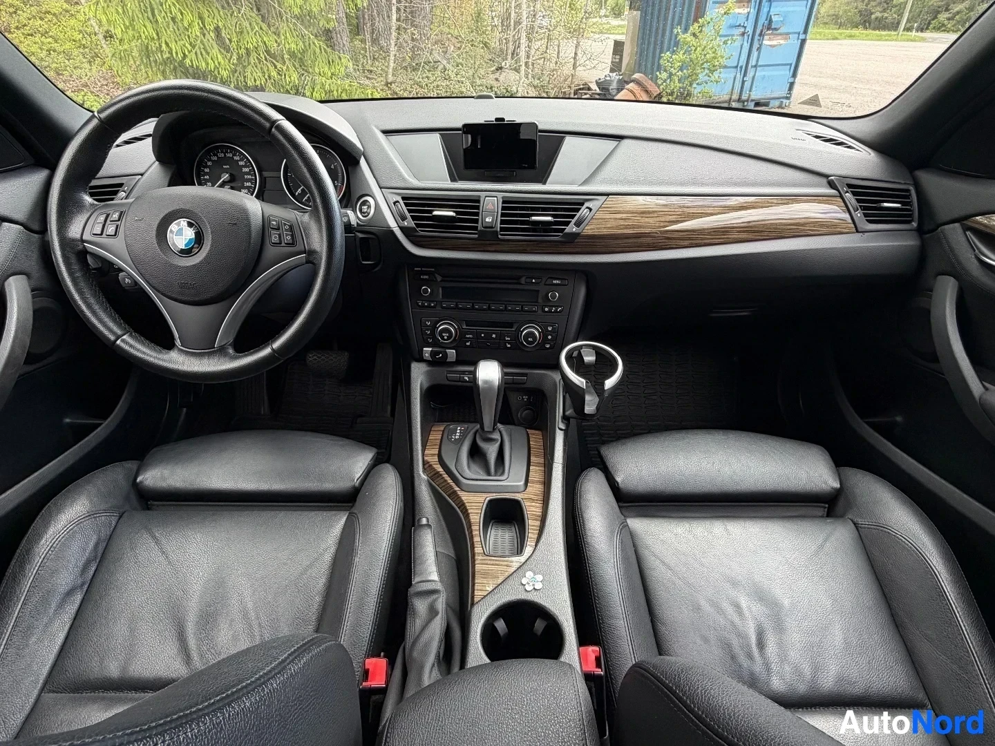 Full dashboard view with steering wheel, wood accents, and center console controls.