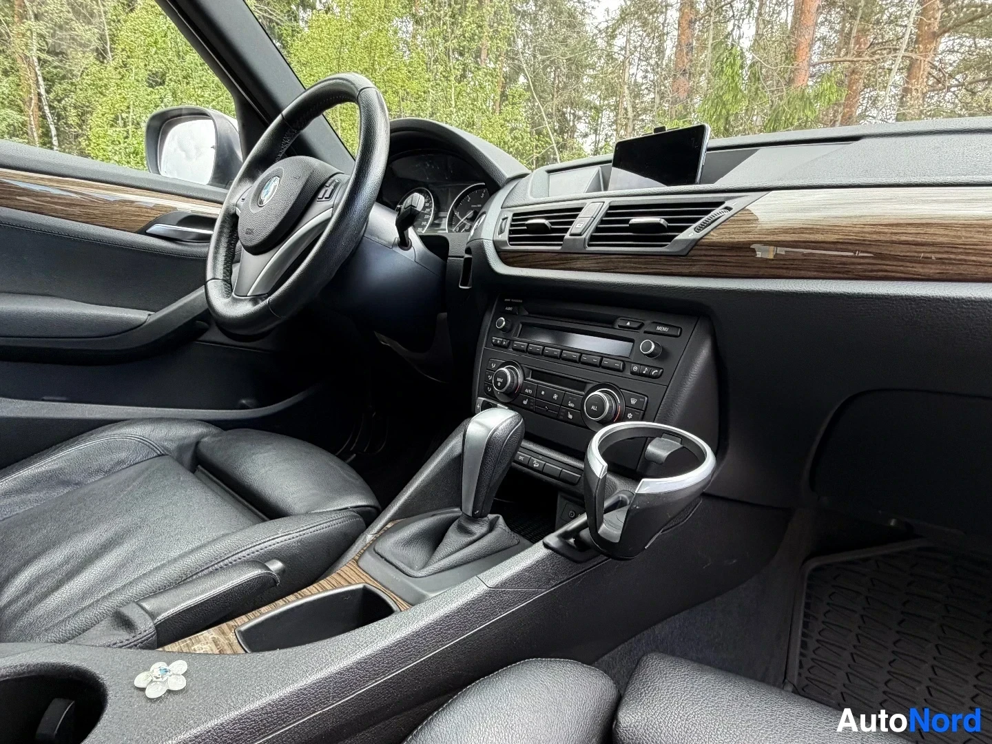 Driver side interior with leather seats, steering wheel, and wood trim details.