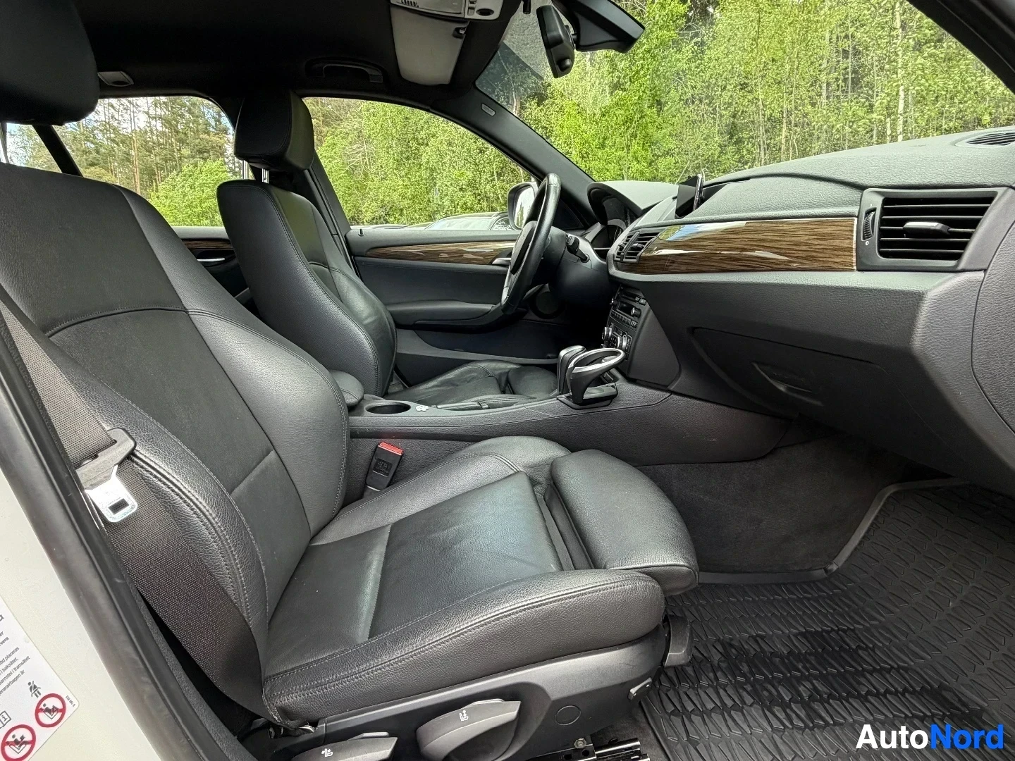Interior front driver and passenger seats with black leather upholstery and wood trim