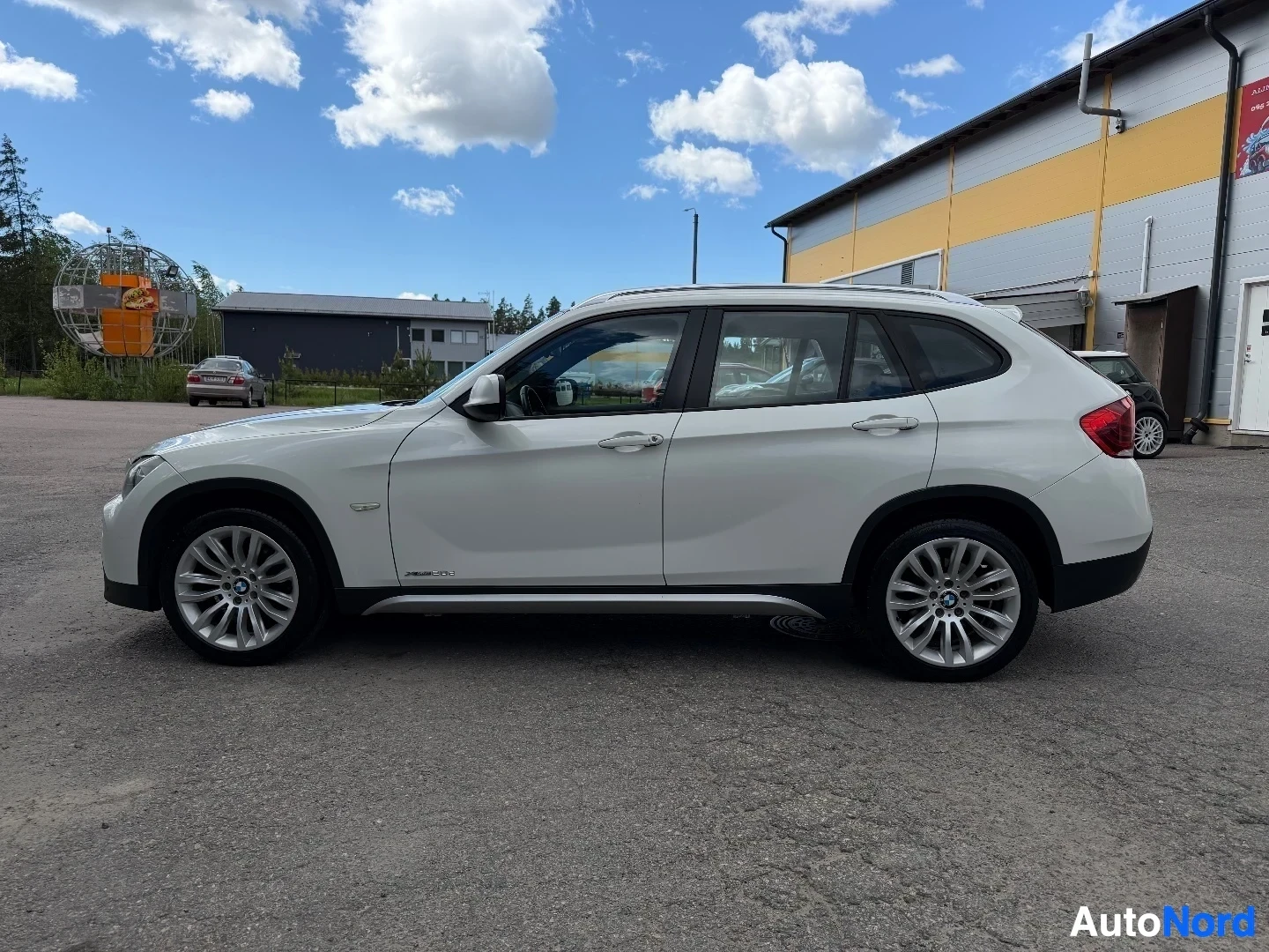 White BMW X1 SUV shown from driver side profile in outdoor dealer lot
