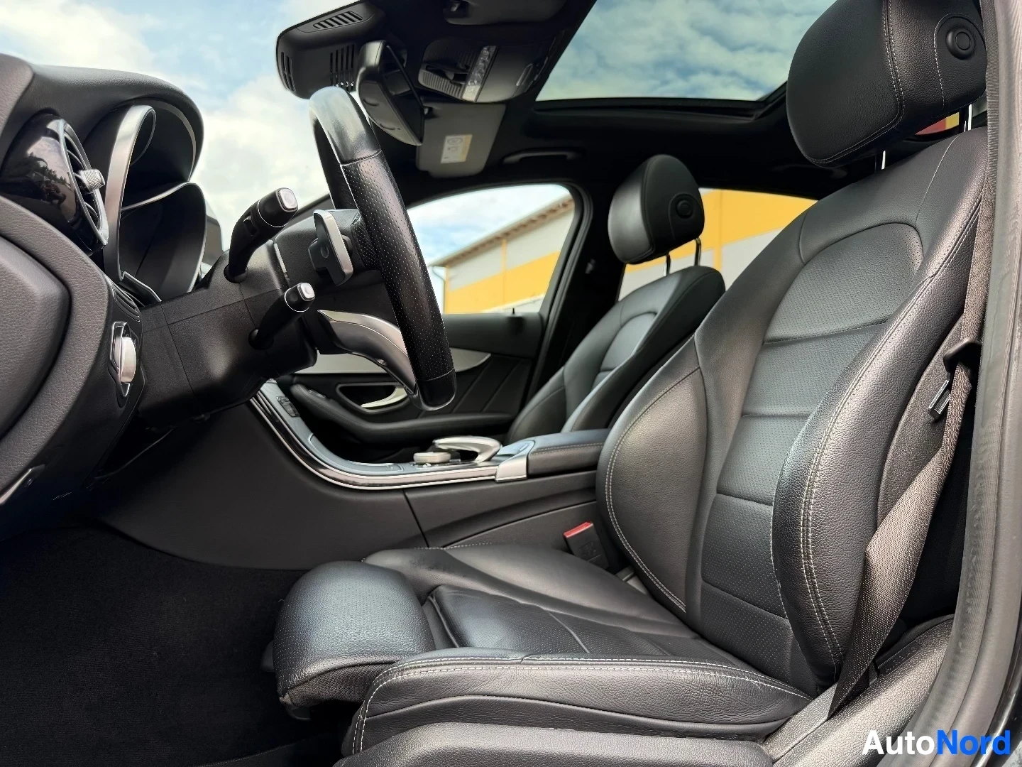 Interior view showing black leather steering wheel and dark gray seats