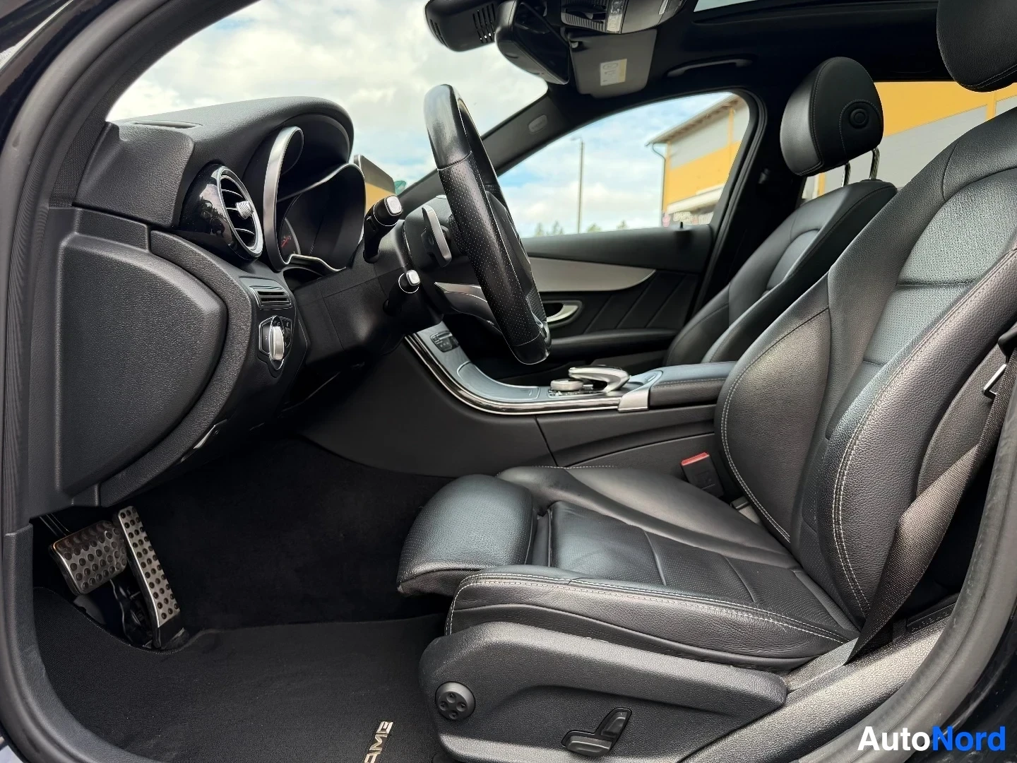 Interior dashboard and steering wheel with panoramic sunroof visible
