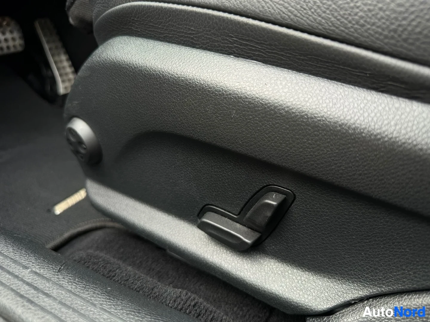 Close-up of seat adjustment control on door panel armrest