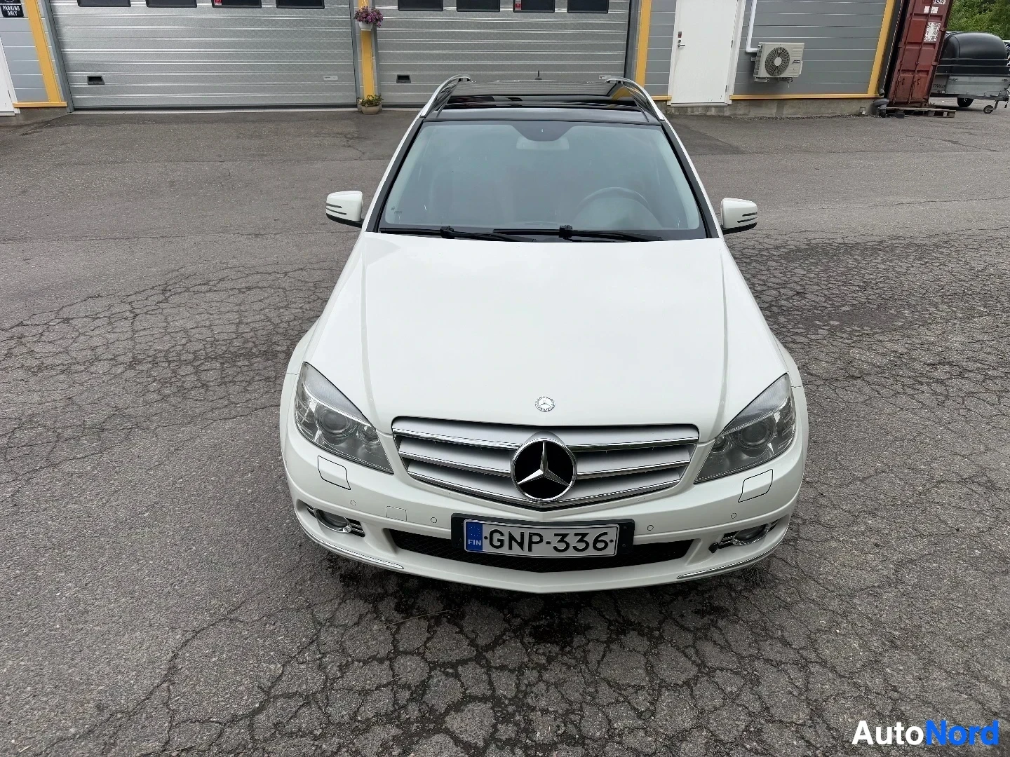 White Mercedes-Benz wagon viewed directly from front with parking lot background