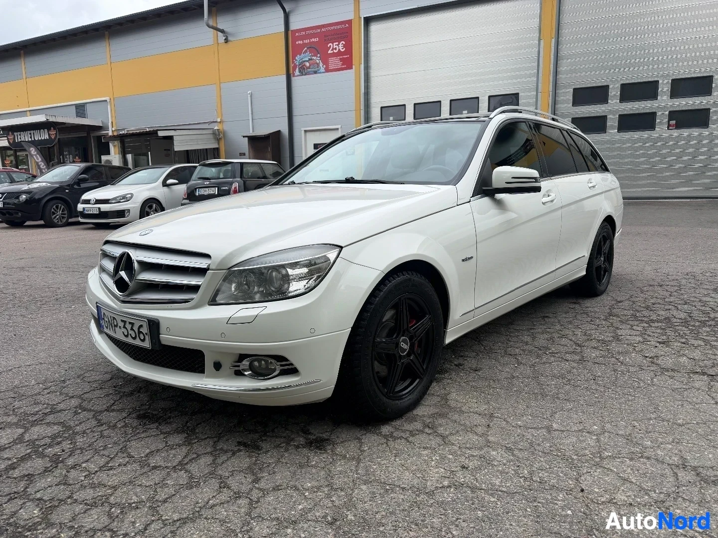 White Mercedes-Benz wagon front view with dealership building background