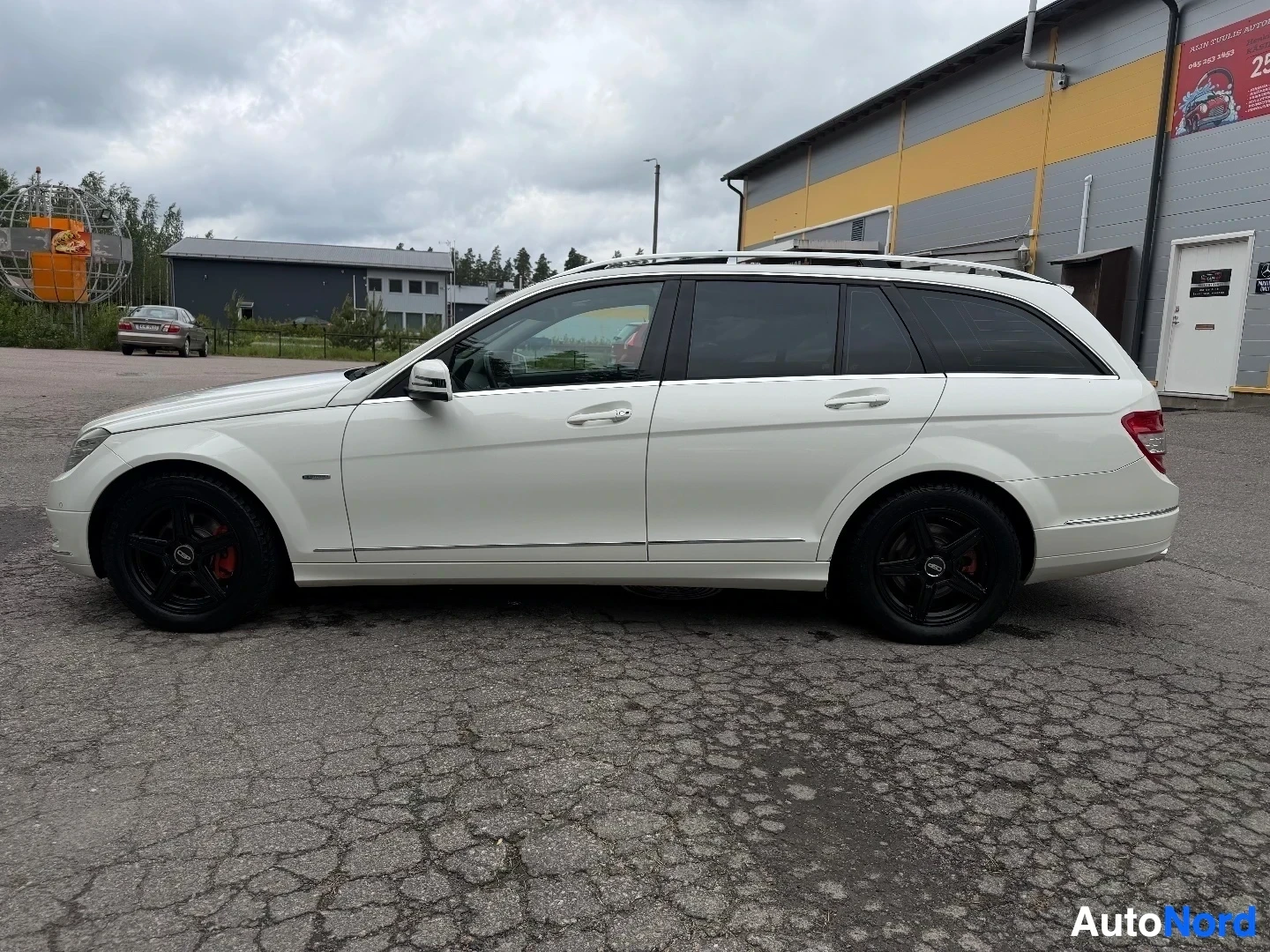 White Mercedes-Benz wagon viewed from side profile in lot