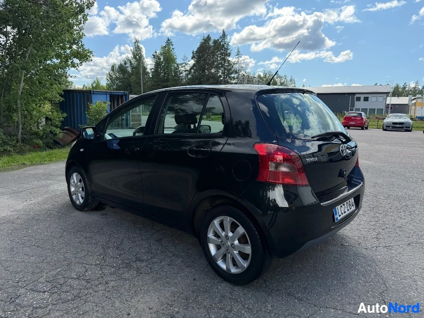 Black Toyota Yaris five-door hatchback, rear three-quarter view with forest background