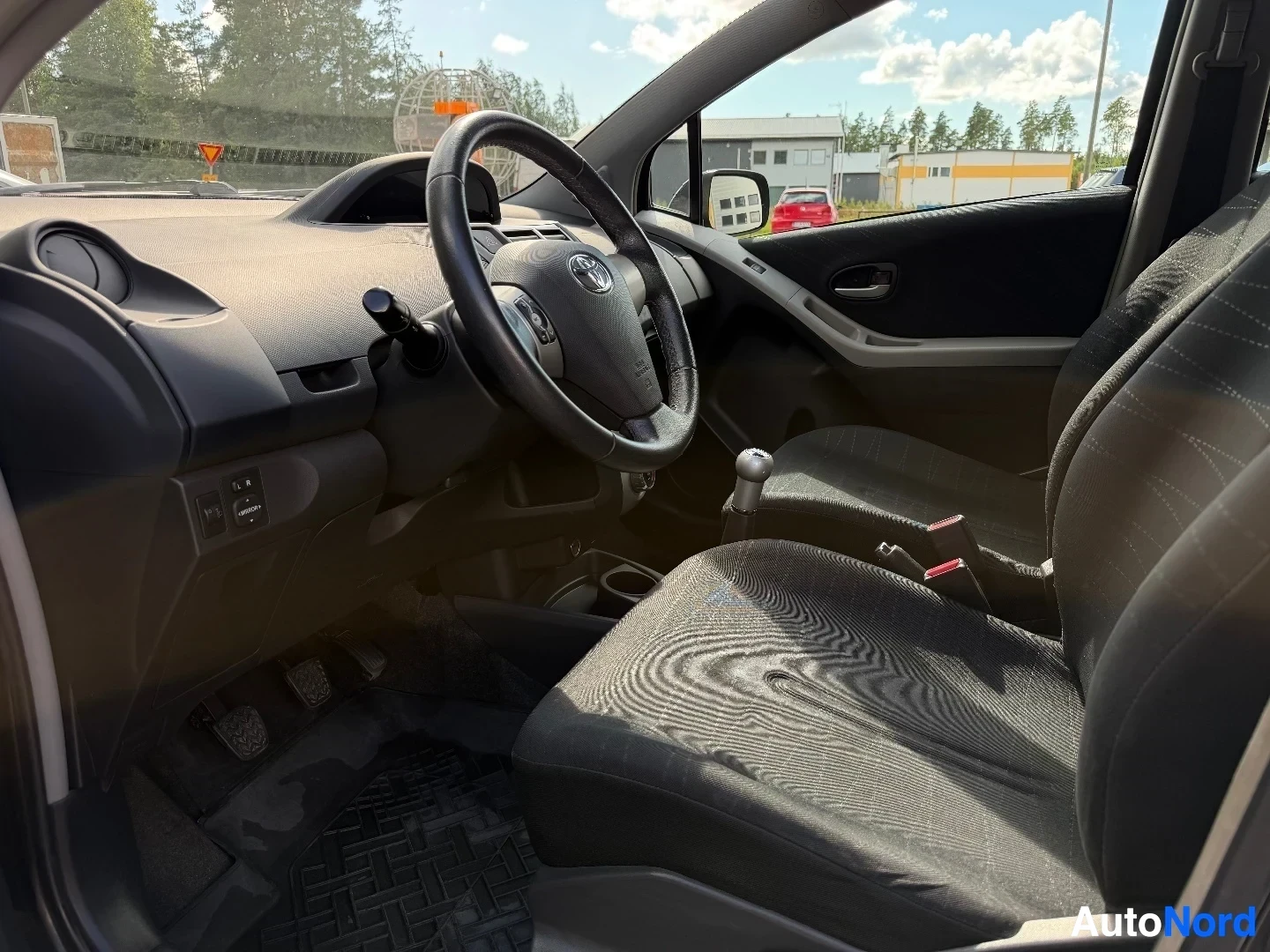 Interior view showing steering wheel, dashboard, and front seats with patterned upholstery
