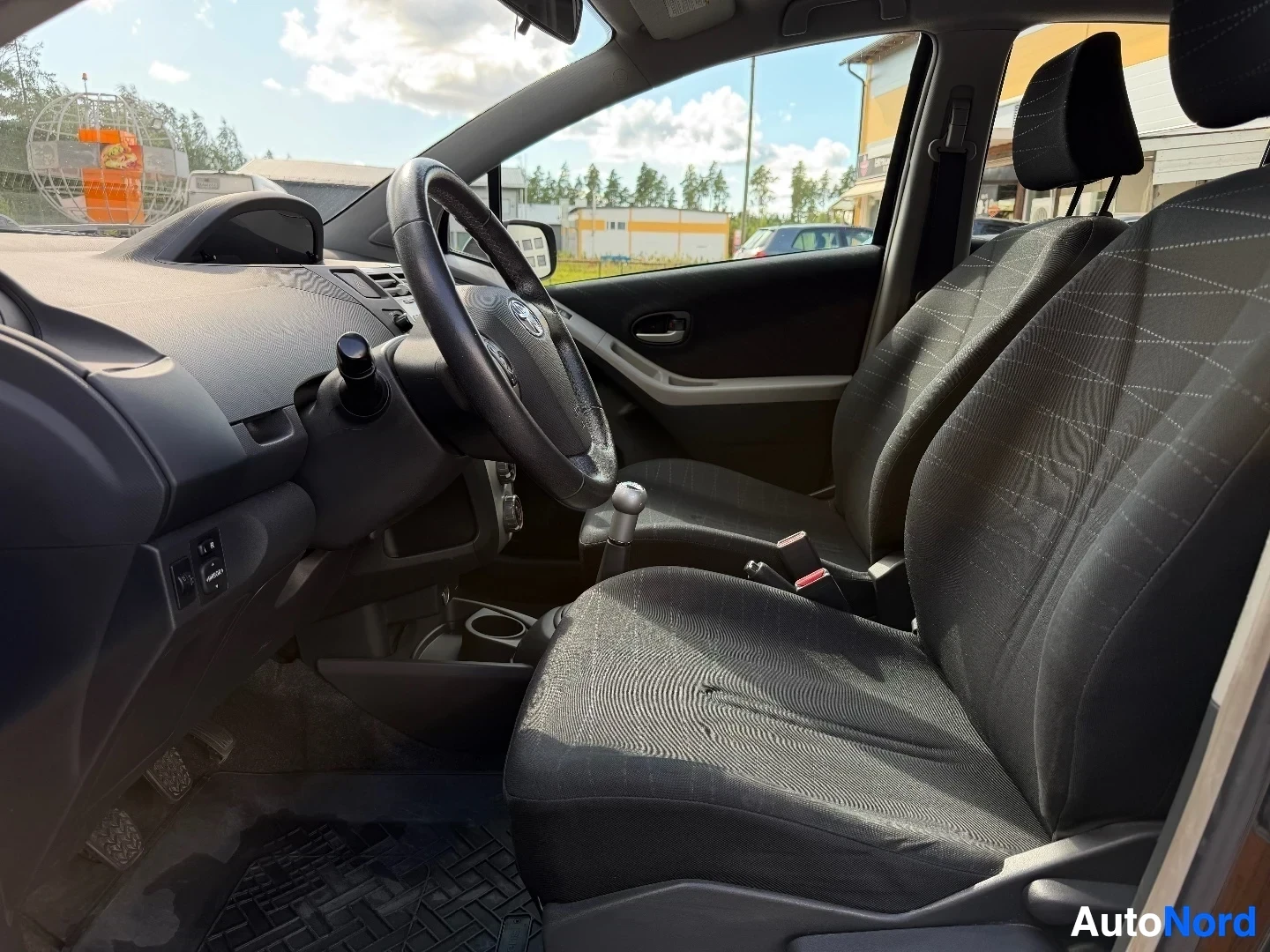 Interior side view of front seats and steering wheel with patterned fabric upholstery