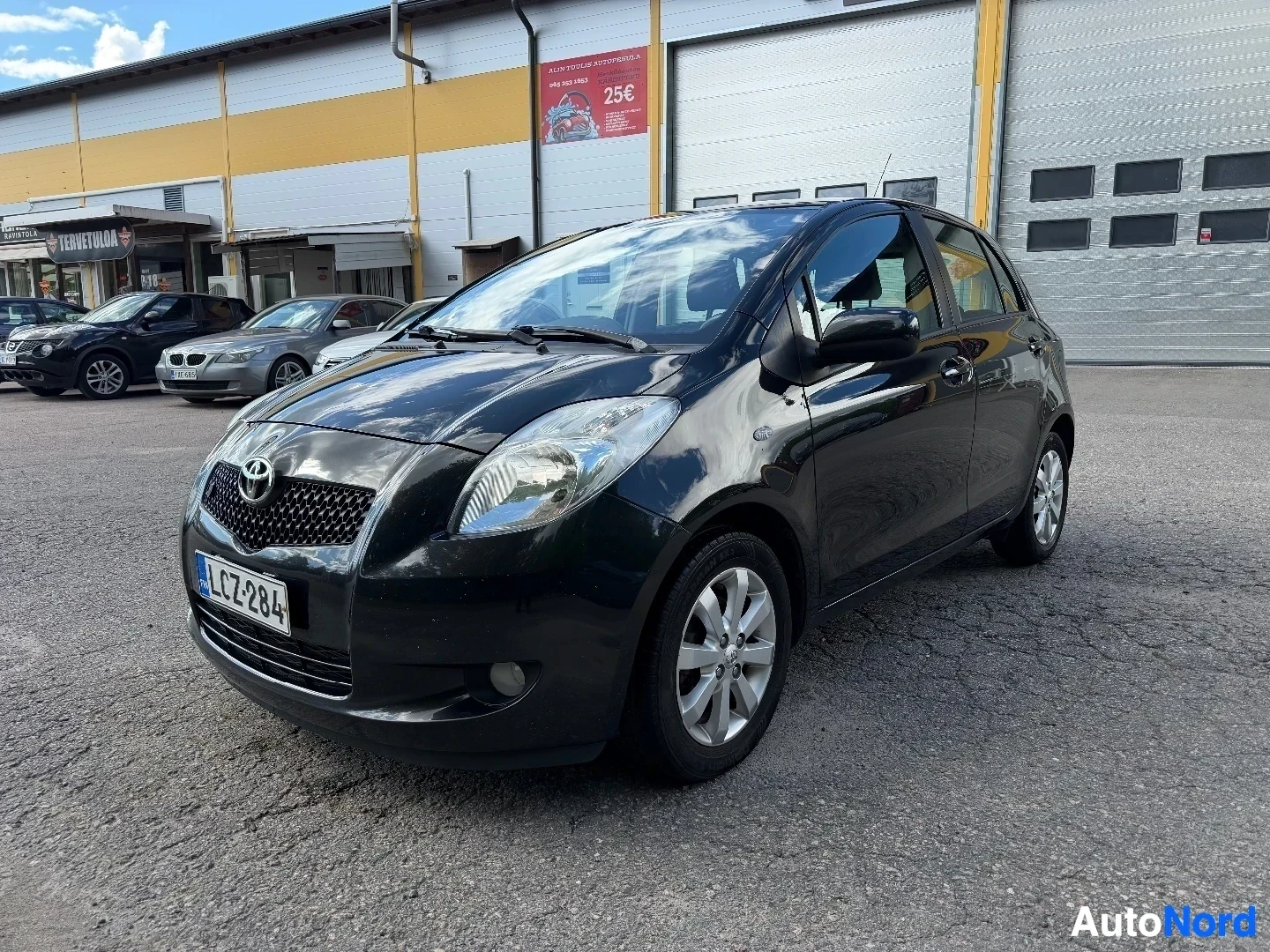 Black Toyota Yaris front three-quarter view in dealer lot with other vehicles