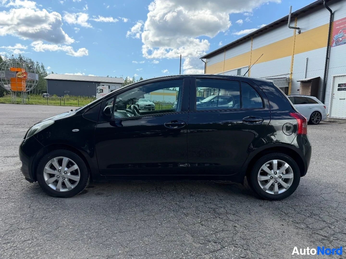 Black Toyota Yaris five-door hatchback, full side profile view on asphalt