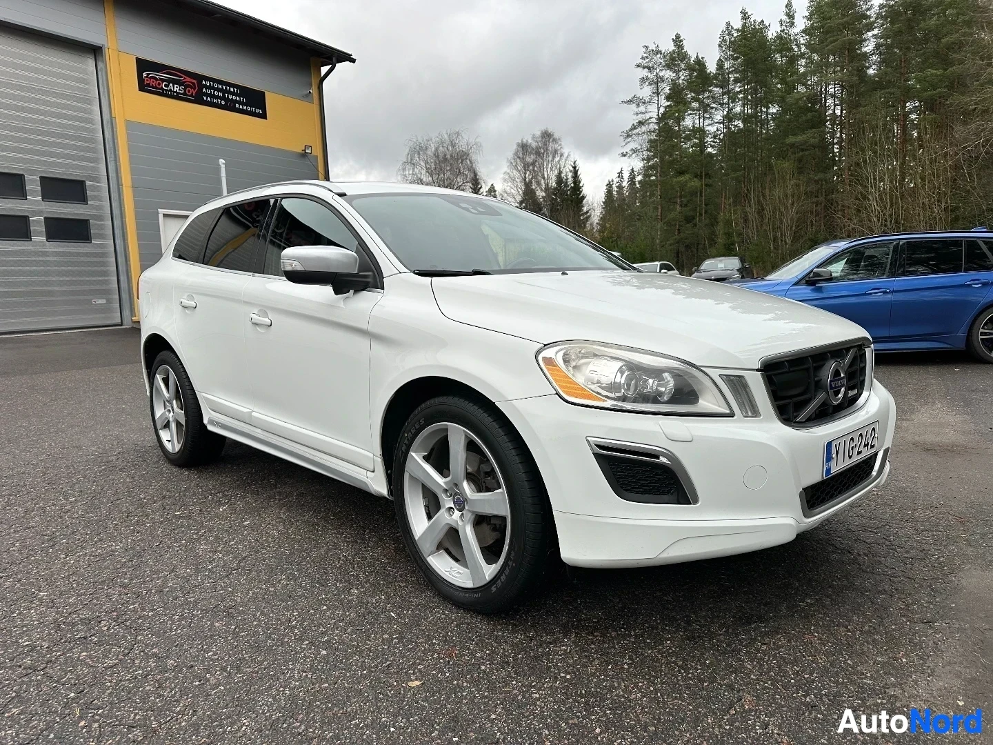 Valkoinen Volvo XC60 näkyy autotallin edessä kolmen neljäsosan kulmasta